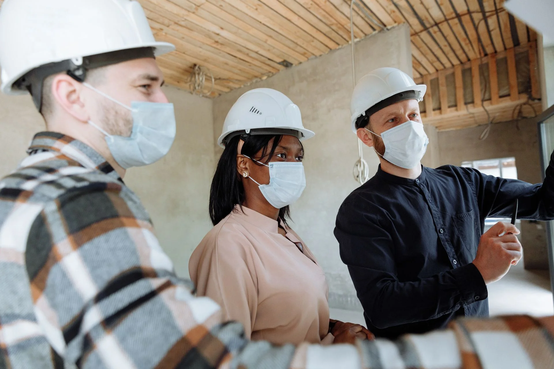 Profissionais de capacete participam de uma conversa em ambiente de obra.