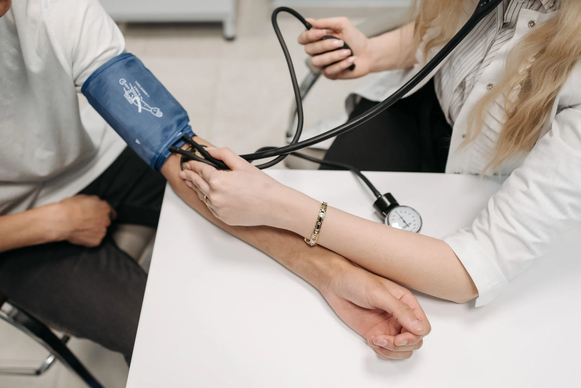 Profissional de saúde verifica a pressão arterial de uma pessoa em consulta.